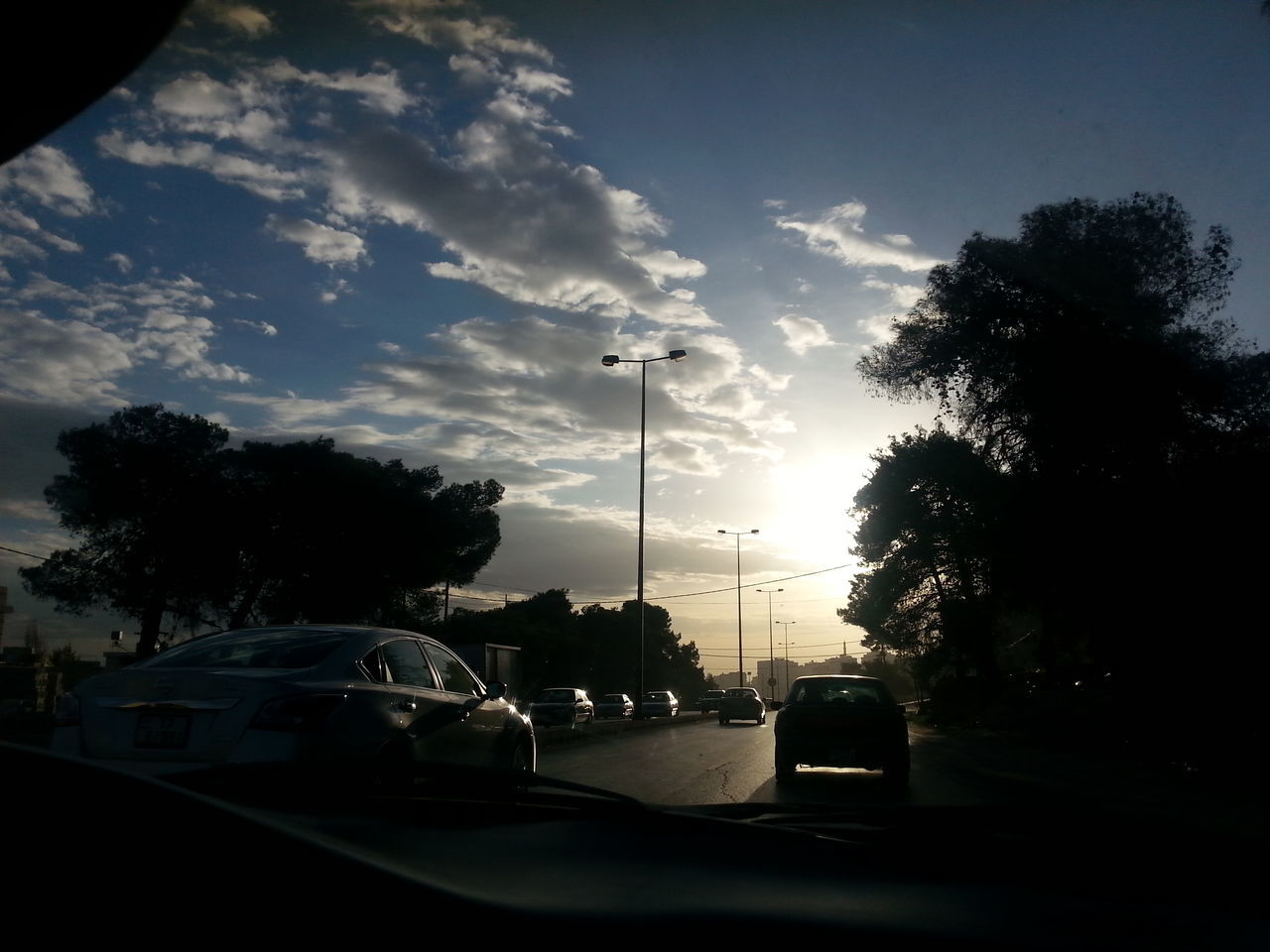 transportation, car, land vehicle, road, street light, tree, sky, street, mode of transport, silhouette, the way forward, sunset, cloud - sky, city, on the move, sunlight, city street, cloud, traffic, road marking