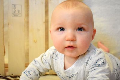 Close-up of cute baby boy looking away while lying on floor at home