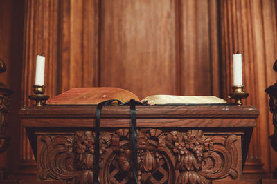 Open book on wooden podium against wall