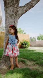 Girl standing on tree trunk against sky