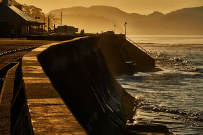 Pier over sea against sky during sunrise