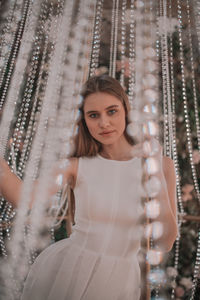 Portrait of young woman standing against wall