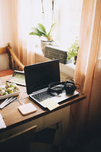 High angle view of laptop with headphones by window on table at home