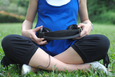 Midsection of woman holding mobile phone while sitting on land