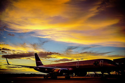 Airplane at airport against sky during sunset