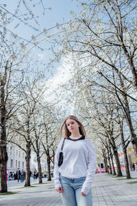 Portrait of young woman standing against bare trees