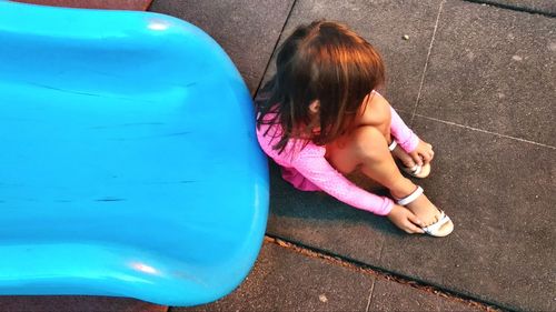 High angle view of sad girl sitting by slide at playground