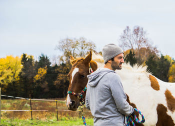 Side view of man with horse standing at pen