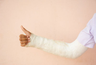 Cropped fractured hand against wall