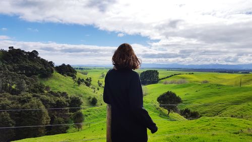 Rear view of woman standing on field against sky