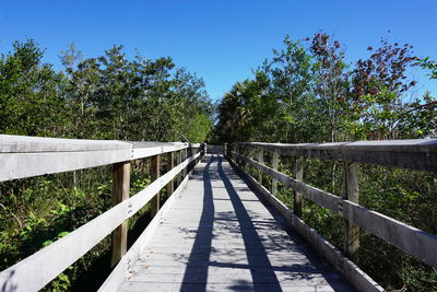 Footbridge amidst trees against clear sky