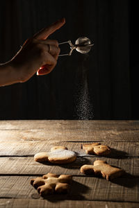 Close-up of hand dusting powder sugar on cookies