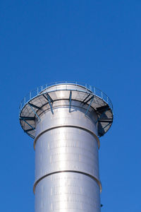 Low angle view of smoke stack against blue sky