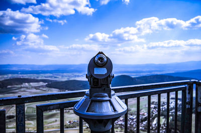 Close-up of coin-operated binoculars by sea against sky