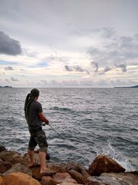 Rear view of man looking at sea against sky