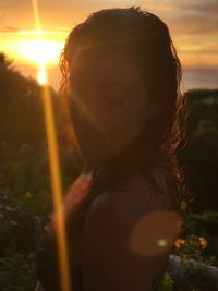 Woman standing on field against sky during sunset