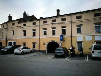 Cars parked on road by building against sky