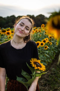 Portrait of smiling young woman amidst sunflowers