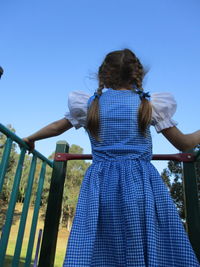 Rear view of girl standing against clear blue sky