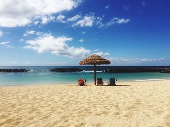 Sun loungers on beach against blue sky