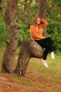 Woman sitting on tree trunk in forest