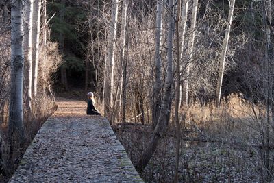 Woman sitting on boardwalk in forest
