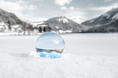 Close-up of crystal ball on snow covered landscape