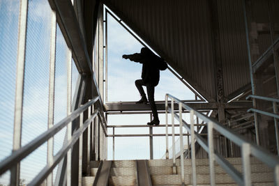 Low angle view of silhouette man standing on railing
