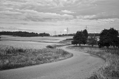 Road amidst field against sky