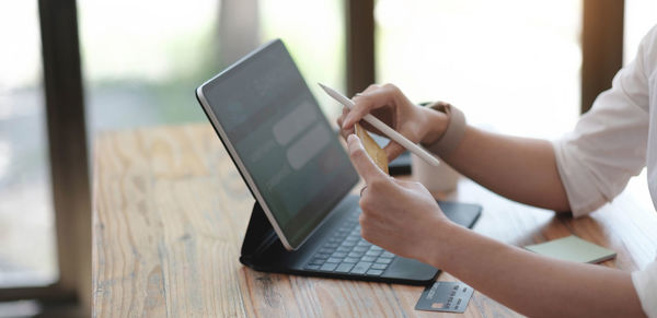 Midsection of man using mobile phone on table