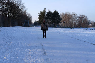 Man on snow covered field against sky