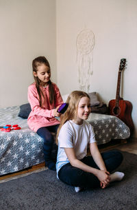 Two girls schoolgirl friends play at home, do their hairstyle