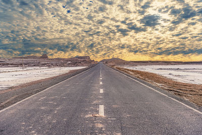 Road passing through land against sky