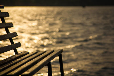 Empty bench by sea against sky