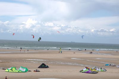 People kiteboarding on sea shore against sky