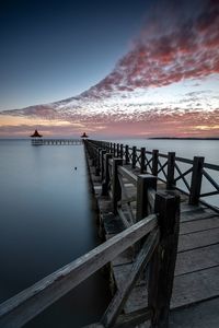 Pier over sea against sky during sunset