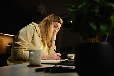 Woman works at home office at night, using laptop