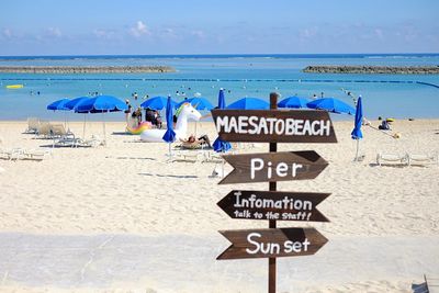 Information sign on beach against sky