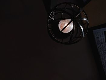Low angle view of illuminated electric lamp against black background