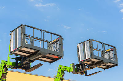 Low angle view lifting platforms against sky