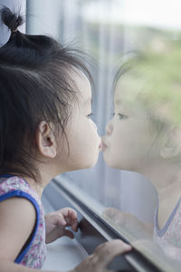Reflection of girl kissing herself in window glass