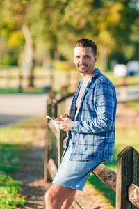 Portrait of young man standing on railing