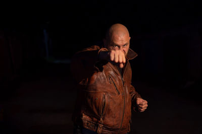 Mid adult man standing against black background