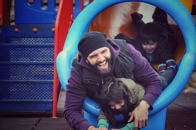 Happy father with children in slide at playground