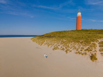 Lighthouse by sea against clear sky