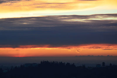 Silhouette of trees against dramatic sky during sunset