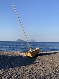 Sailboat on beach against clear sky