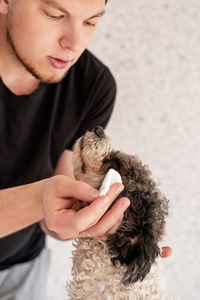 Man playing with dog outdoors against wall