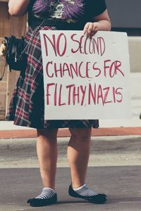 Low section of woman holding text on paper