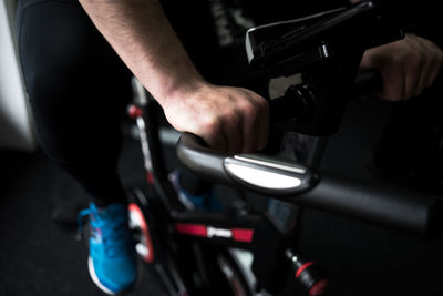 Low section of man riding exercise bike in gym